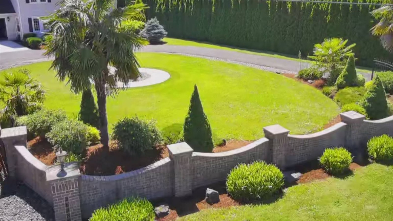 Brick retaining wall with lawn and palms behind it