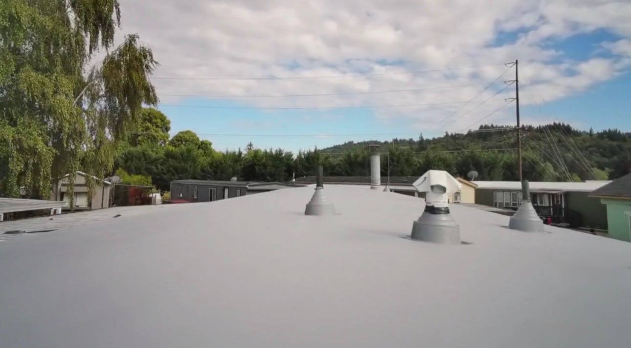 The finished flat roof, smooth gray membrane with sealed vent boots