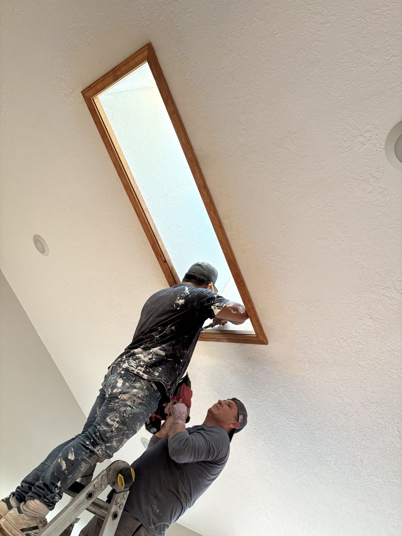 The skylight trim being finished from inside on a ladder