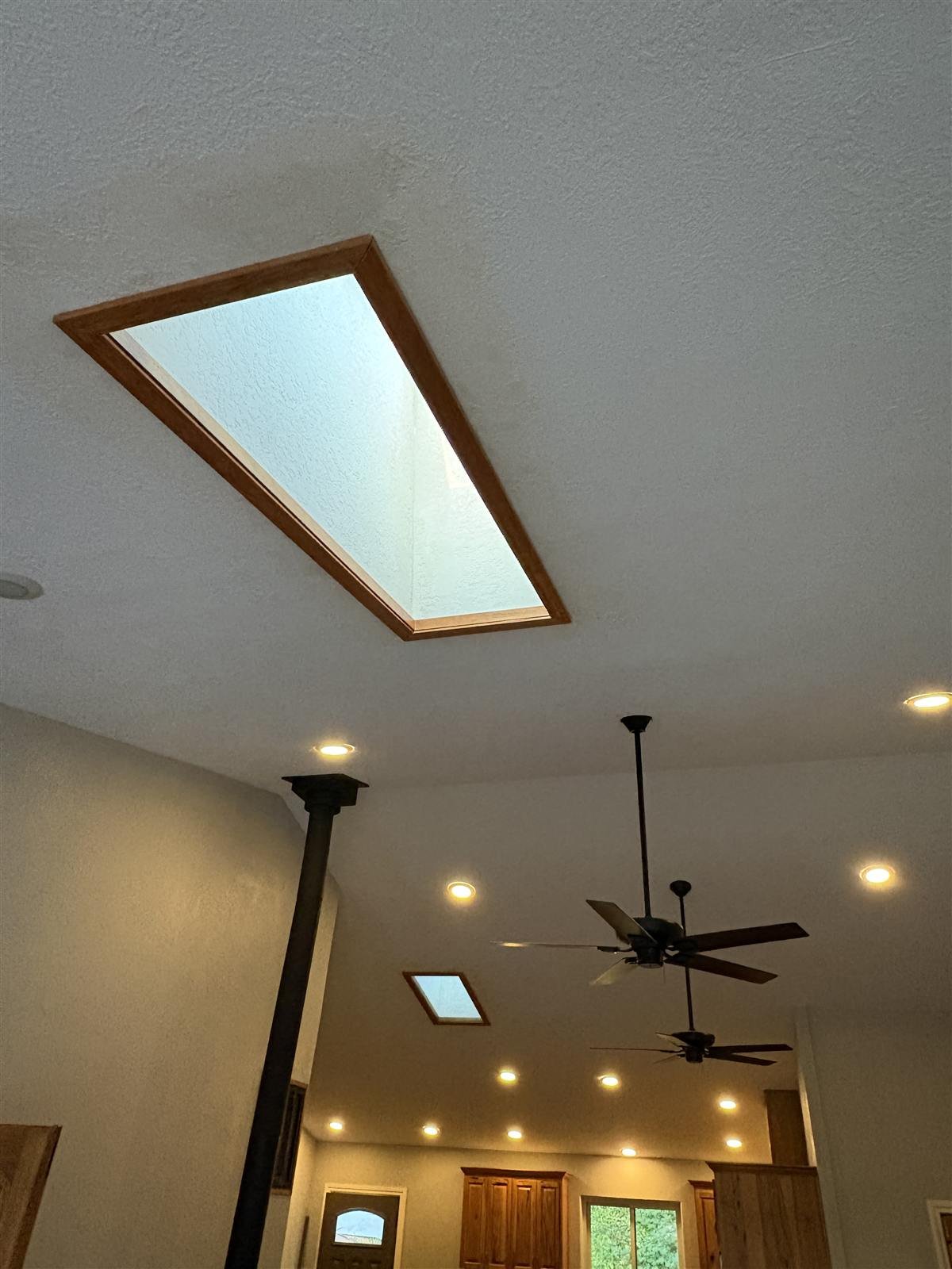A wood framed skylight seen from inside a vaulted ceiling